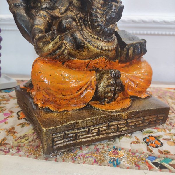 dettaglio della base della statua ganesh color arancione e bronzo